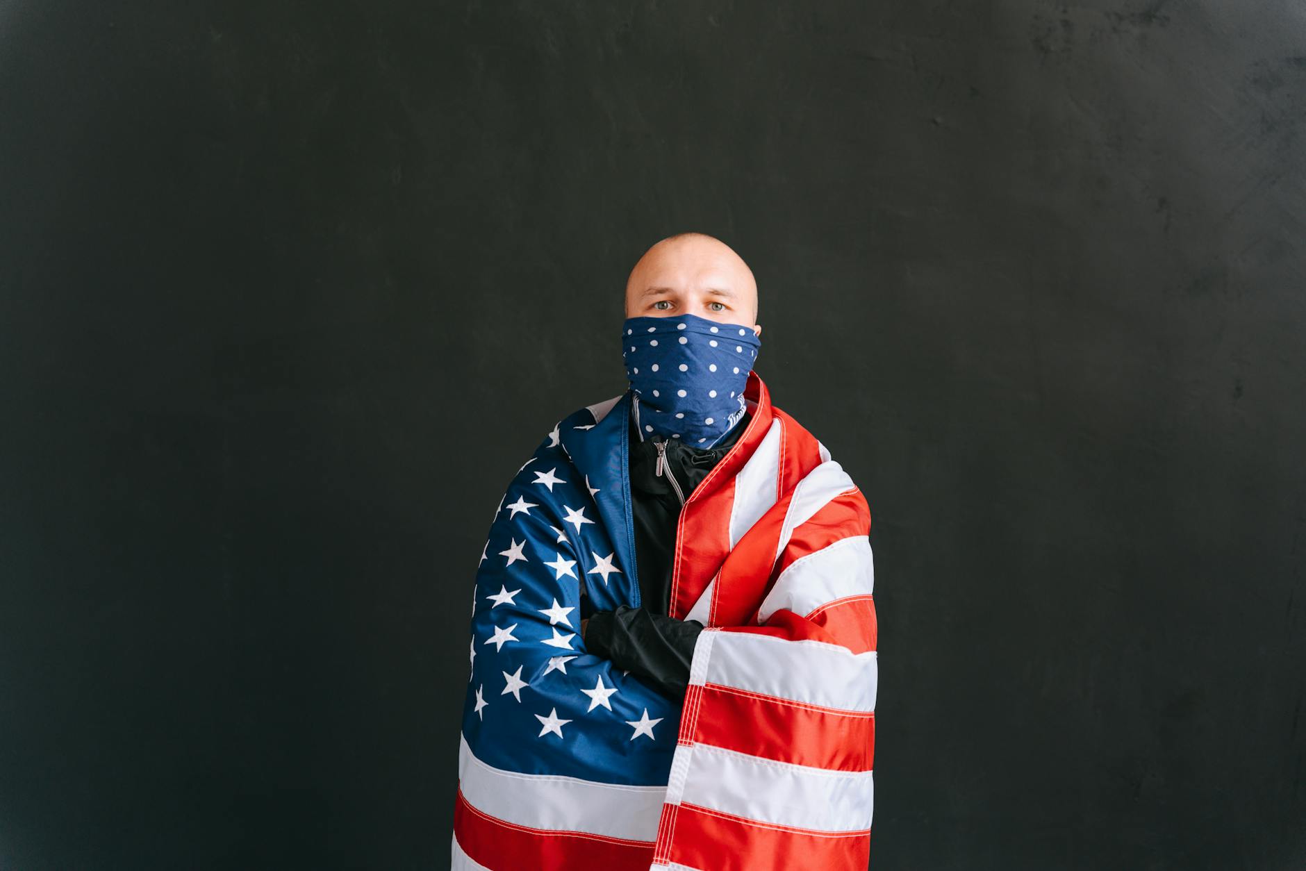 photograph of a man with a united states of america flag crossing his arms